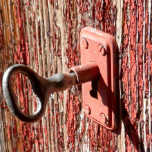 A rustic key partly turned in a lock on a door.