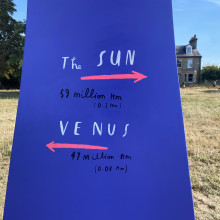 Purple sign saying the distance to the Sun and Venus on the "Our Place in Space" trail