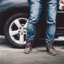 Person wearing jeans standing next to a car