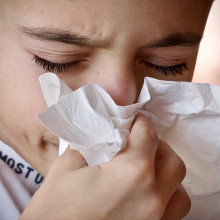 A child with a runny nose and sneezing into a handkerchief