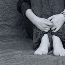 black and white image of someone hugging their knees to their chest