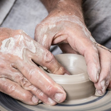 A potter working some clay on a wheel.