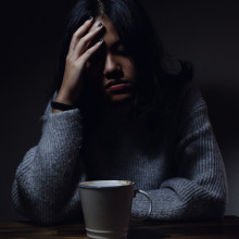 a woman sitting at table, in pain