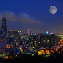 A moon rising over a cityscape