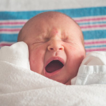 Yawning baby wrapped in cloth