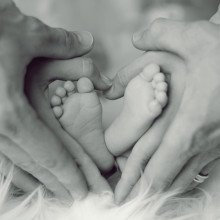 baby's feet, wrapped in parents' hands