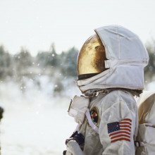 An astronaut in a snowy setting in profile, looking up at the sky