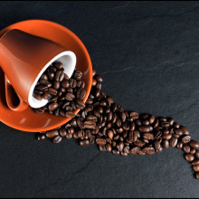 A cup on its side, with coffee beans spilling out of it