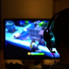 View of a person's head from behind with headphones on playing a video game.
