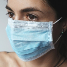 A woman wearing a blue facemask.