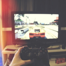 A person holding a controller in front of a TV, playing a car racing game