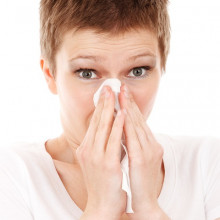 Woman holding a tissue to her nose.