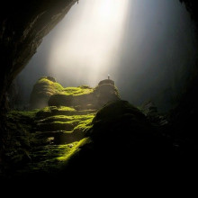 A cave arch with light coming through the ceiling on the other side