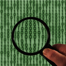 A magnifying glass in front of binary code.