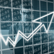 Financial imagery - a young man with glasses behind a rising graph.