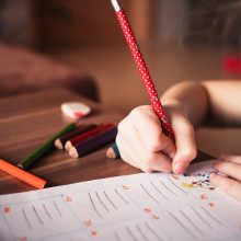 A young girl writing with a pencil.