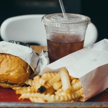 A tray with a burger, chips, and soft drink.