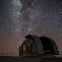 A large astronomical telescope against a dark starry sky.