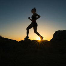 Silhouette of woman running over rocks
