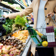 Person putting vegetables in supermarket basket