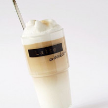 This photograph shows a glass of latte macchiato, which is a hot beverage made from steamed milk and espresso.