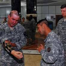 Retired Staff Sgt. Bradley K. Gruetzner explains his prosthetic arm to servicemembers at Al Faw Palace, Camp Victory, Iraq, June 21.